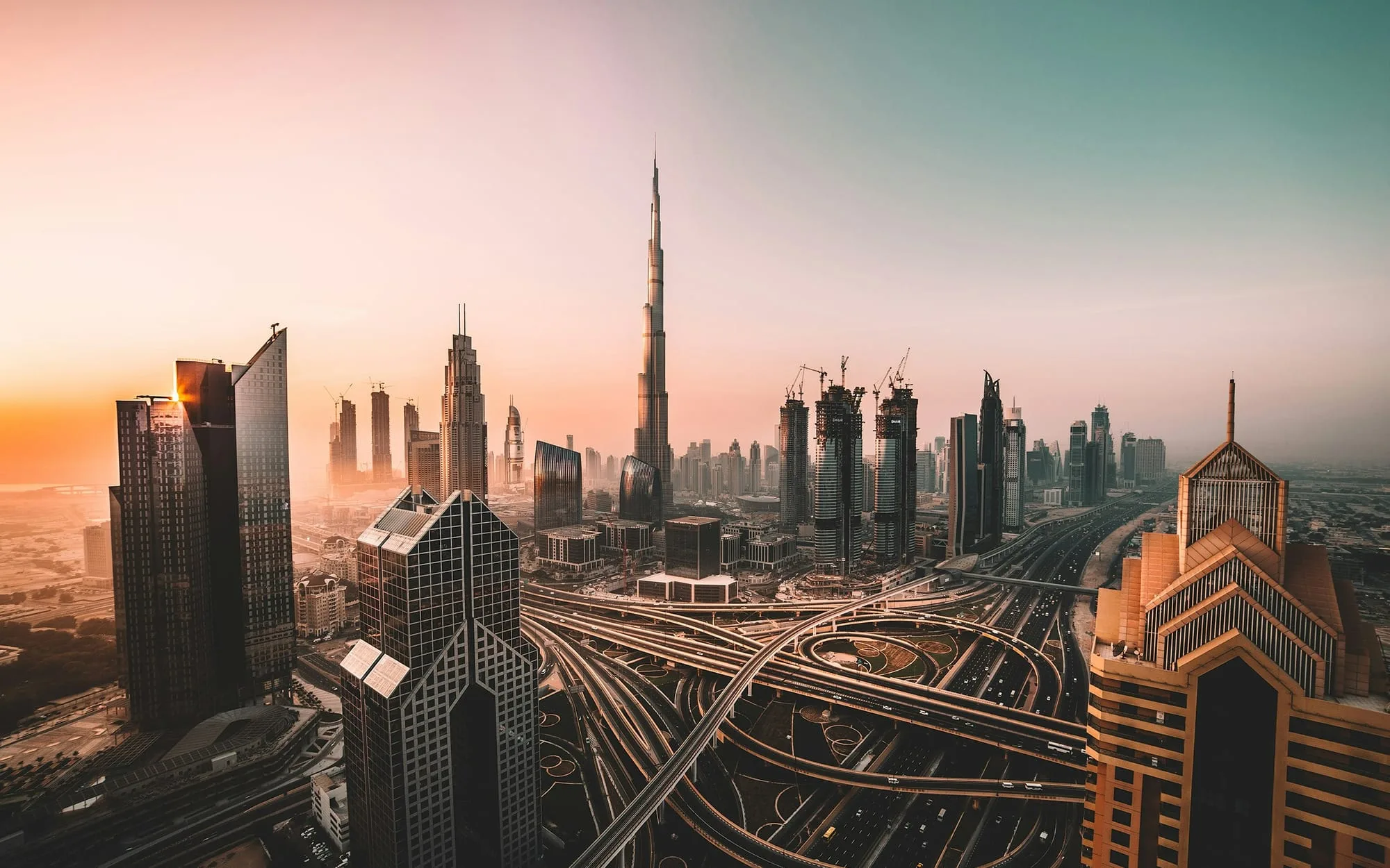 The Burj Khalifa and Downtown Dubai skyline above a highway interchange at dawn