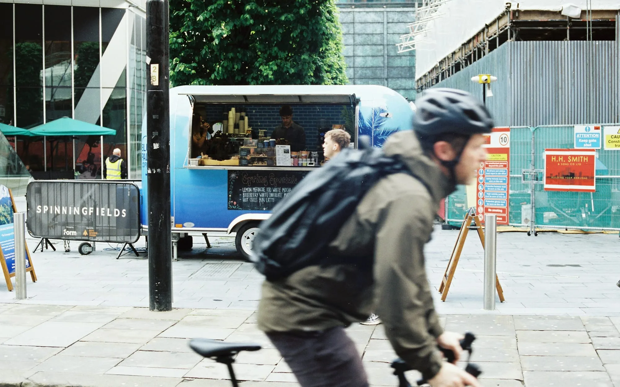 A cyclist passing a street-food van in Spinningfields, Manchester