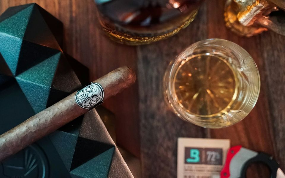 A cigar and a glass of whisky on a wooden table
