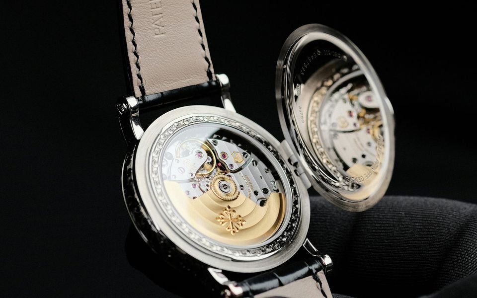 A Patek Philippe held open to show the movement through its case back