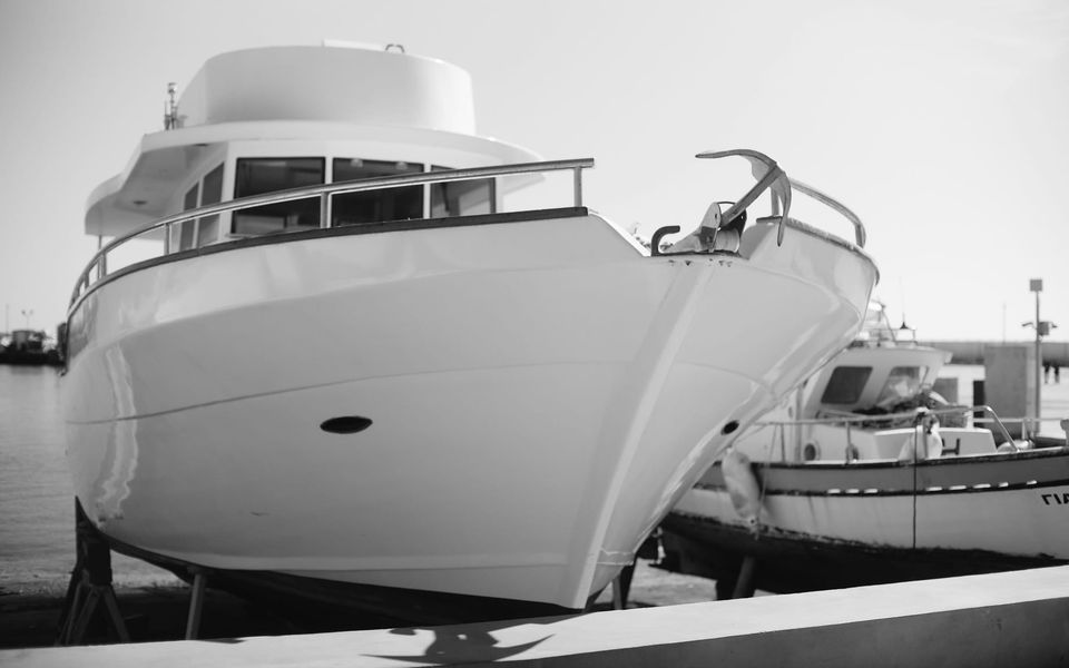 The bow of a white motor yacht out of the water in a boatyard