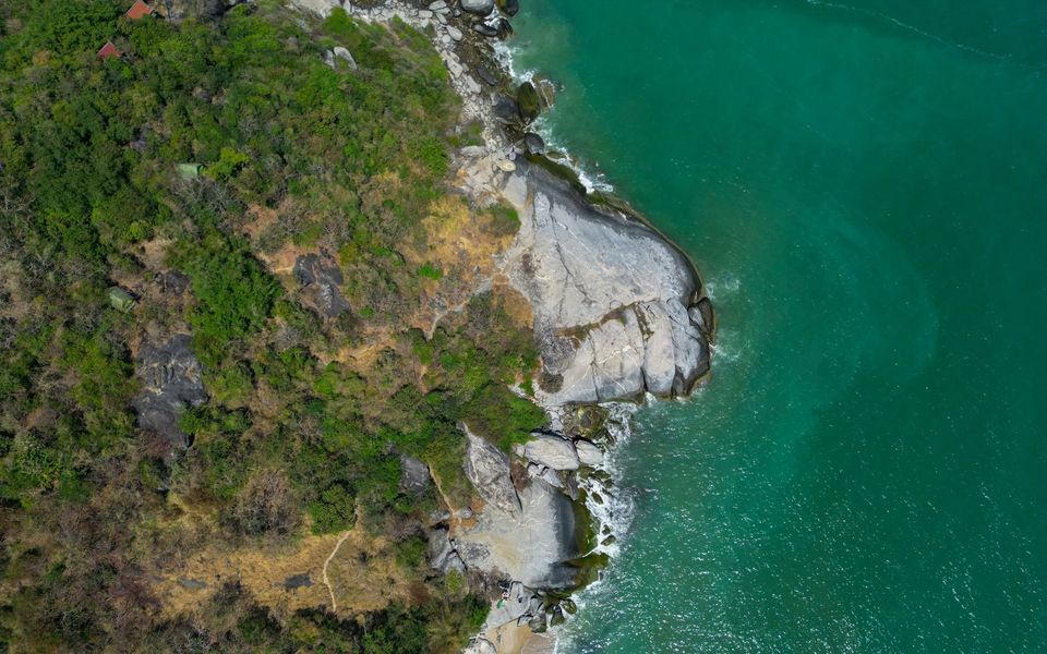 Aerial view of a rocky headland and green sea on the Hua Hin coast