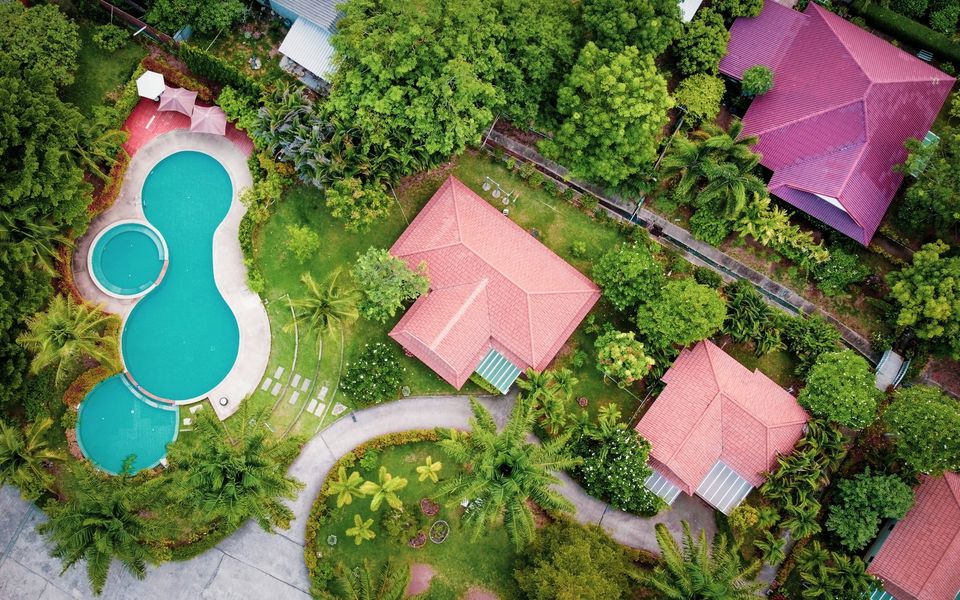 Aerial view of tiled villa roofs, gardens and a shared pool in Chalong, Phuket