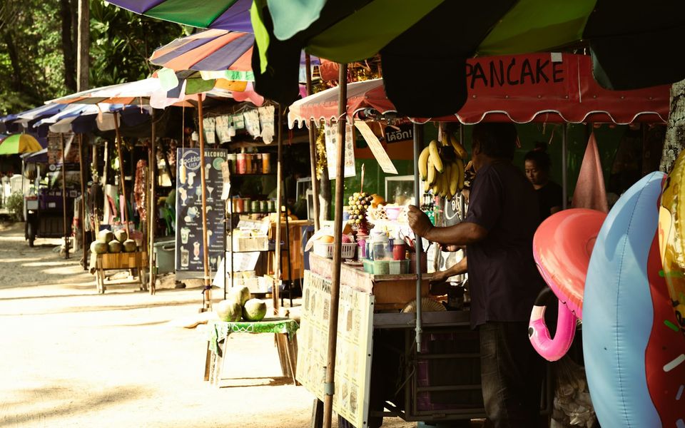 Street-food stalls under umbrellas on the beach road behind Surin Beach