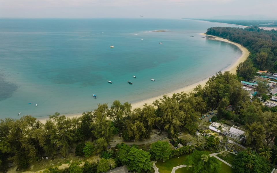 Aerial view of Nai Yang Beach's curving bay, with the airport runway and Mai Khao beyond